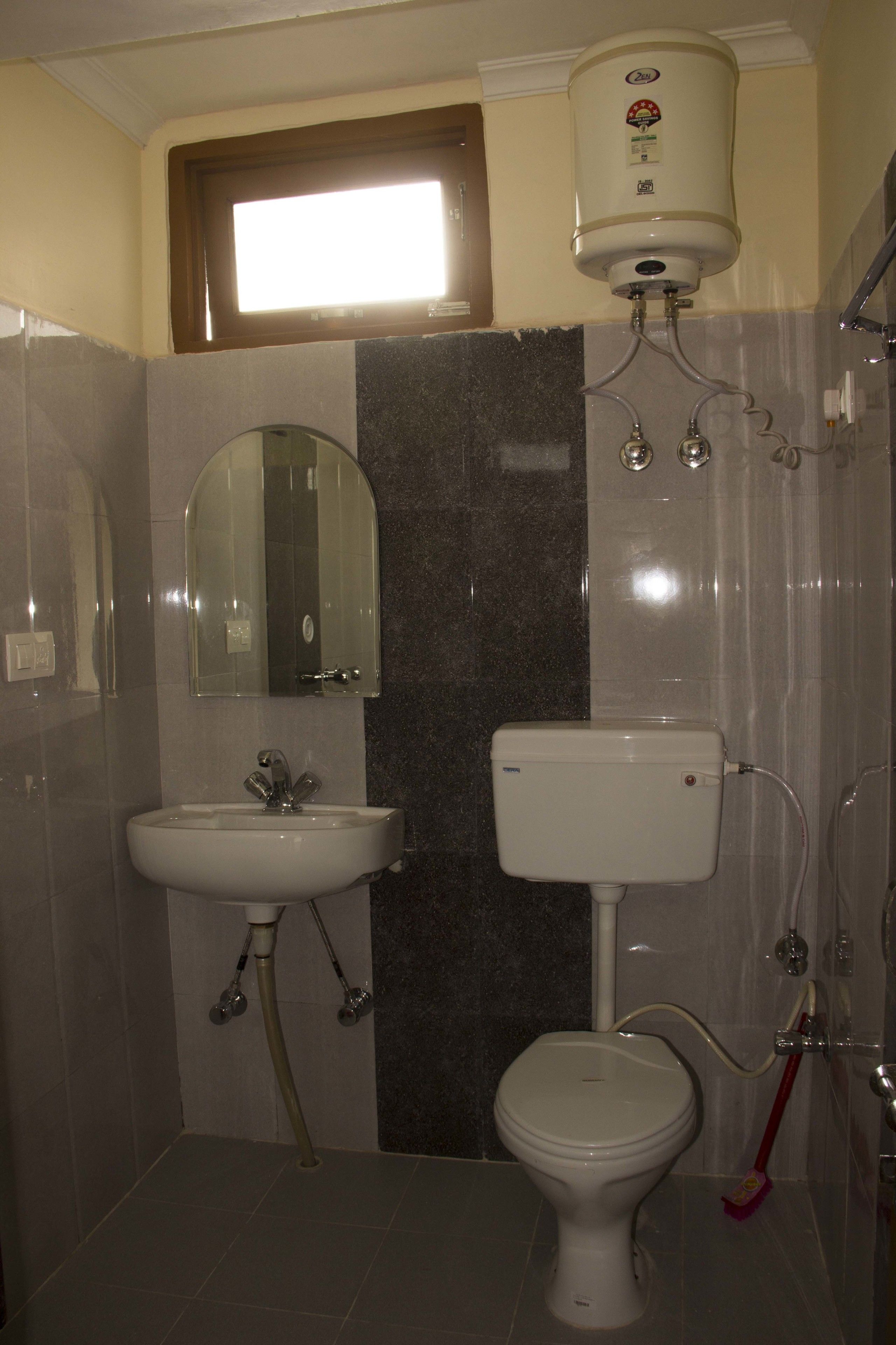 A bathroom with a toilet, sink, and a window above the sink.