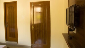 Two wooden doors, a television on a wooden stand, and a light switch on the wall. - Hotel Hill Town (Dharamshala)