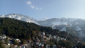 A mountainous village with snow-capped peaks in the background and a cluster of buildings in the foreground. - Hotel Hill Town (Dharamshala)