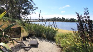 Un chemin de gravier mène à un espace aménagé avec des chaises et une table, d’où l’on a une vue sur un lac bordé d’arbres.