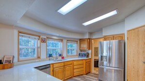 Una cocina moderna con armarios de madera, un refrigerador de acero inoxidable, un microondas y un lavavajillas.