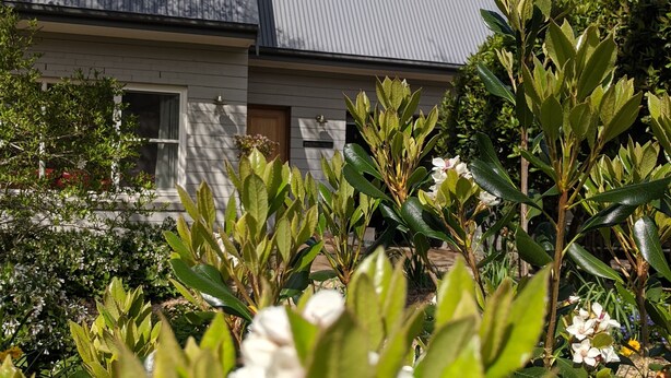 A house with a grey roof and white siding, surrounded by a garden with various plants and flowers. - Cherrywood - Luxury retreat - with complimentary EV charging (Exeter)