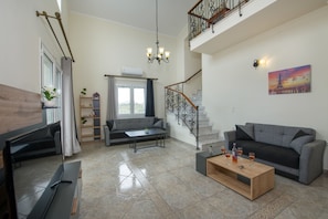 A spacious living area with a staircase, a sofa, a coffee table, and a painting of the Eiffel Tower. - Villa Ifigeneia with Indoor Hot Tubs (Chania)