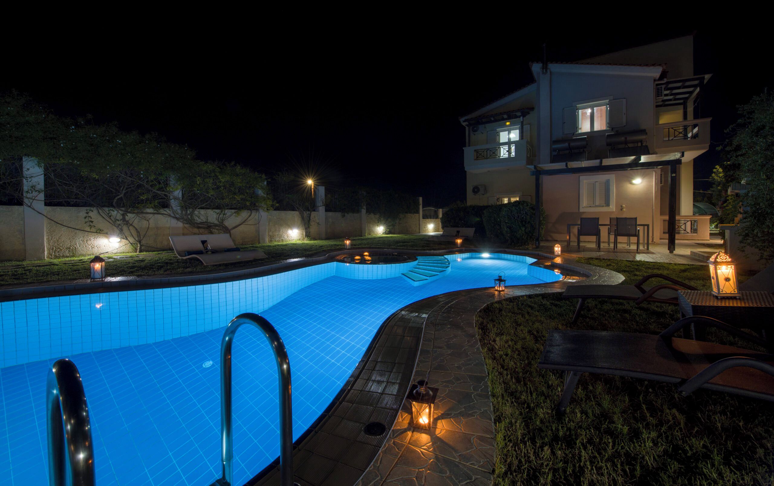 Una piscina de diseño curvo, rodeada por un solárium de piedra y mobiliario exterior.