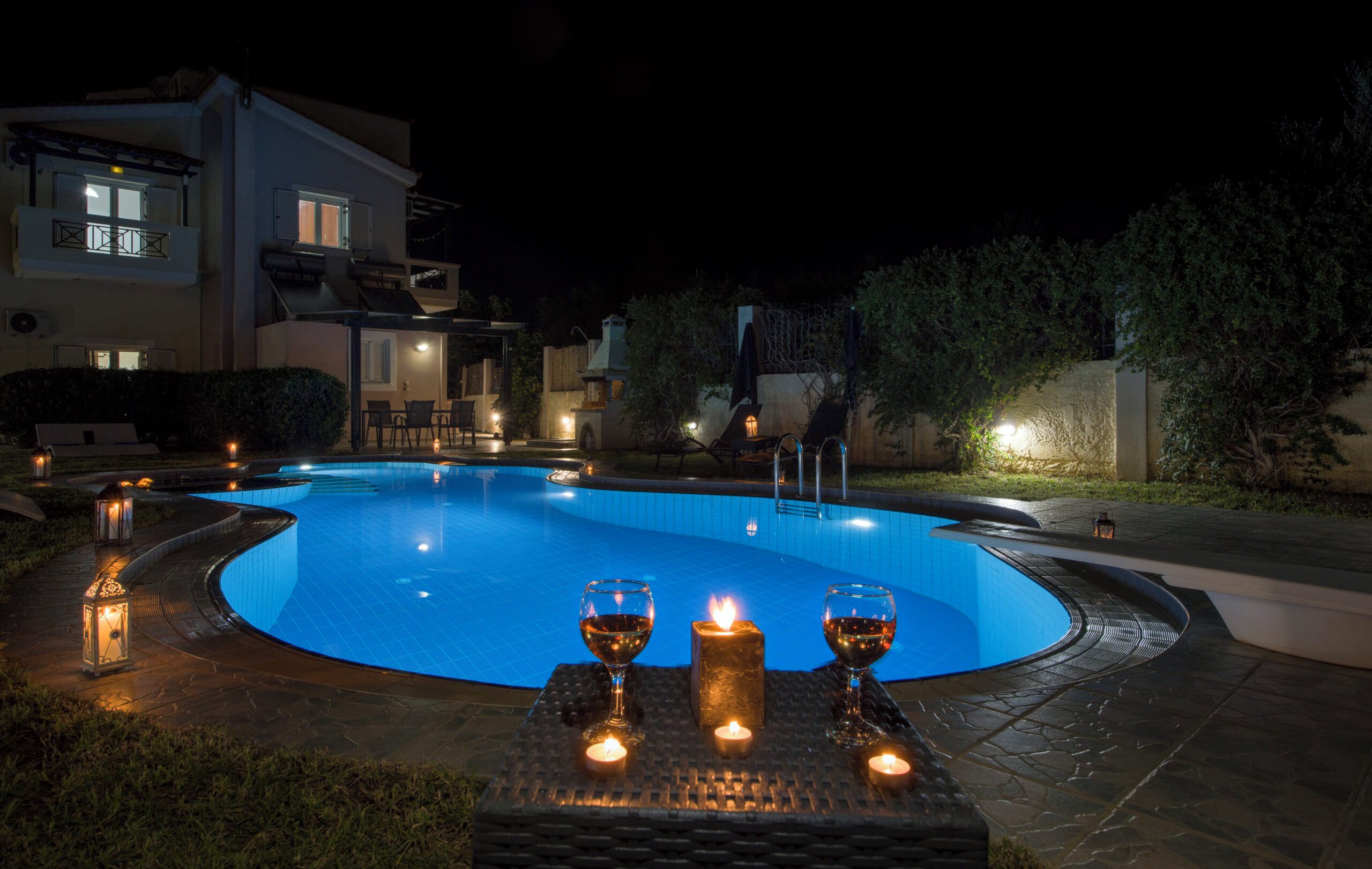 Une piscine entourée d’une terrasse, avec des espaces de détente en plein air et un éclairage d’ambiance.