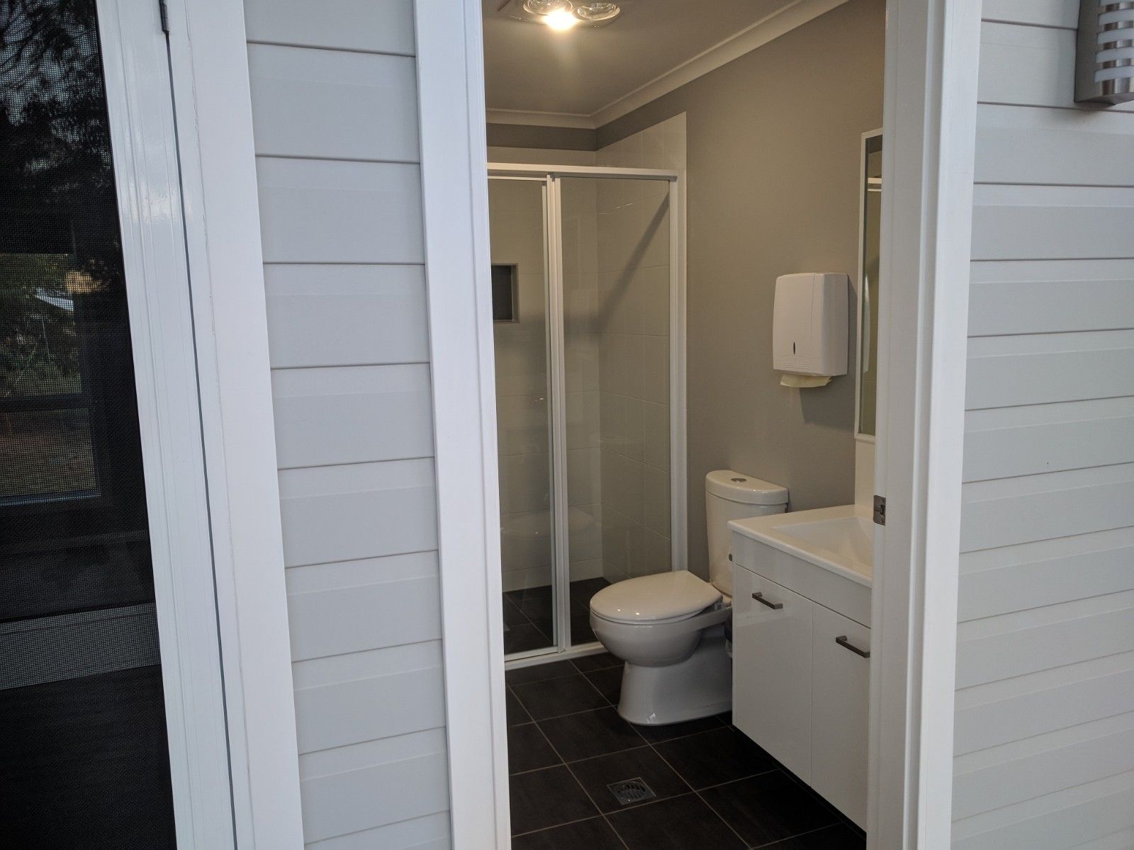 Un baño con inodoro, cabina de ducha y lavamanos.