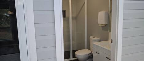 Un baño con inodoro, cabina de ducha y lavamanos.