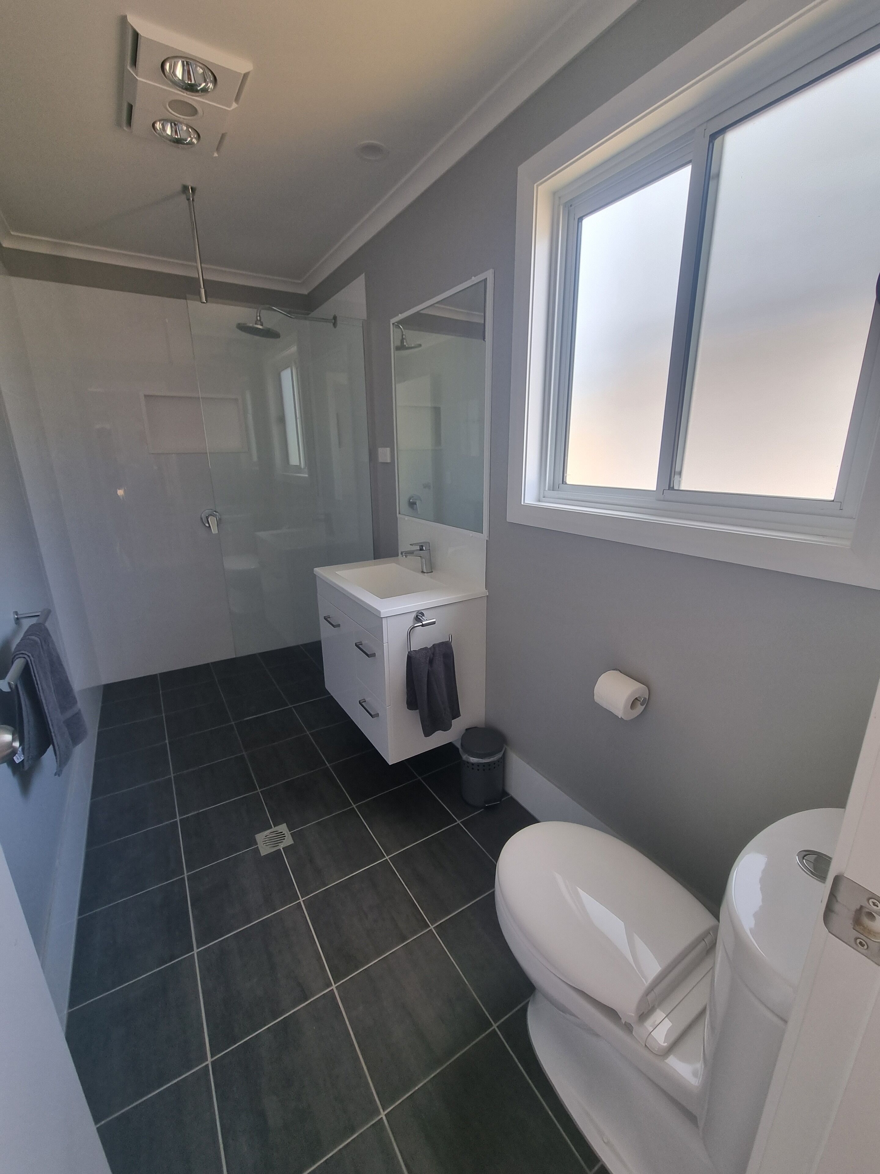 A modern bathroom with a shower, toilet, and sink.