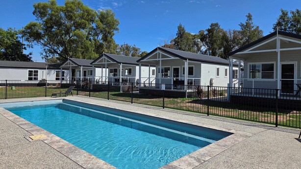 Une piscine dotée d’une terrasse carrelée, entourée d’une clôture noire.