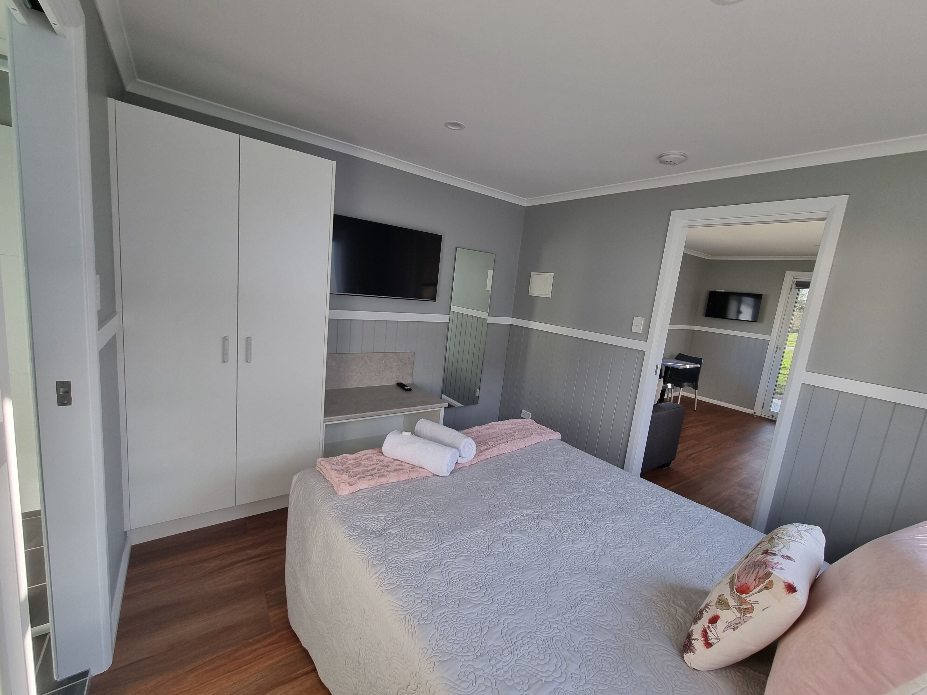 A bedroom with a bed, a wardrobe, a TV, and a mirror.