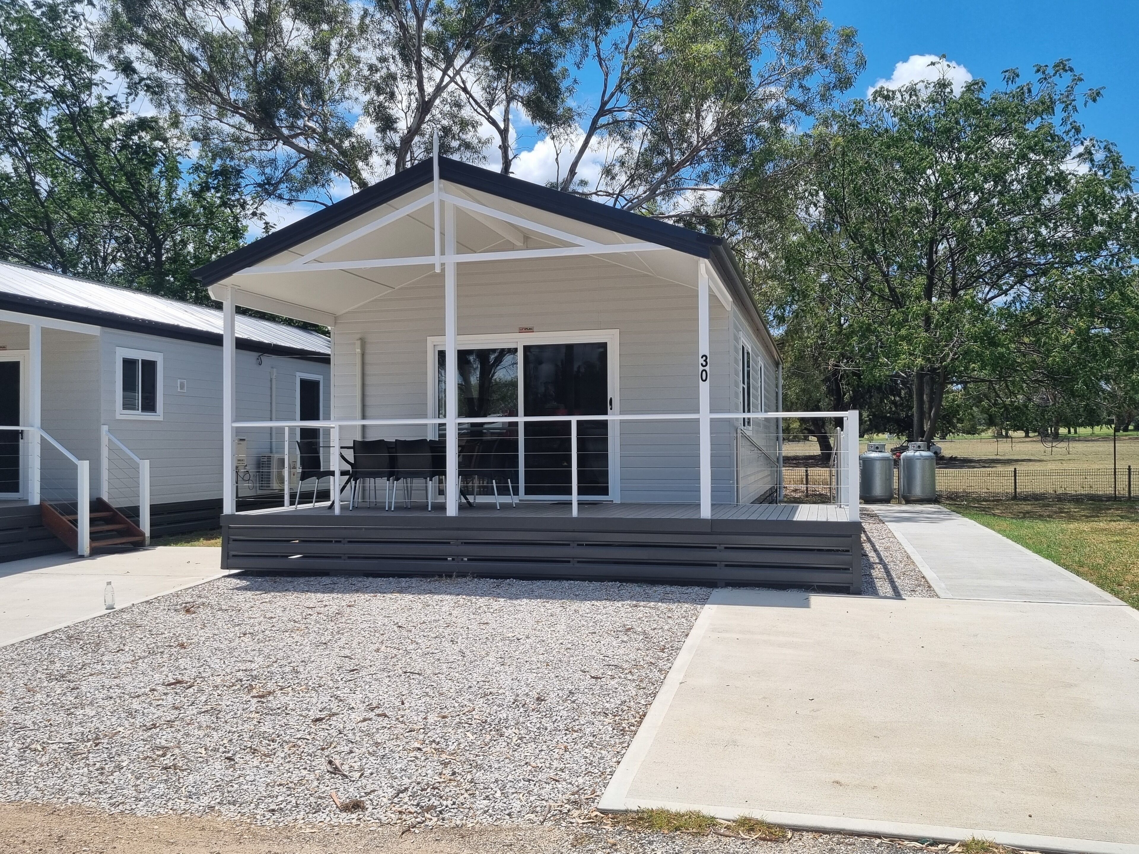 A covered outdoor area with a staircase leading to a door, surrounded by gravel and a concrete path.