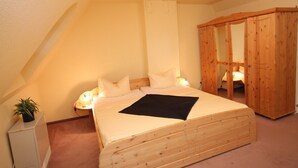 Een slaapkamer met een houten bed, een kledingkast en een bureau met een plant.
