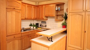 Een keuken met houten kastjes, een wit aanrecht en een spoelbak.