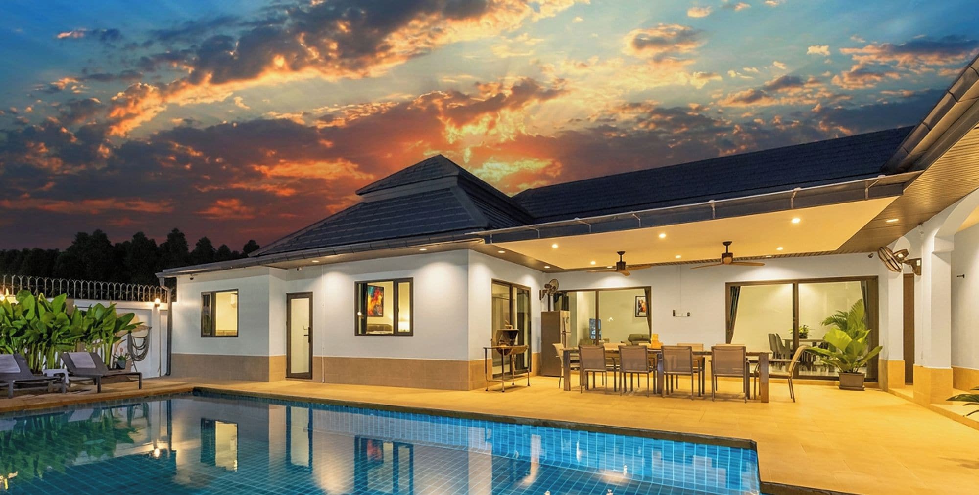 A modern house with a swimming pool, outdoor seating, and a sunset view.