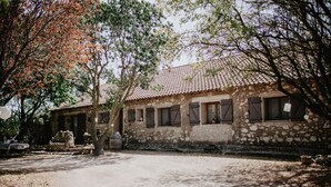 A rustic stone building with a tiled roof, multiple windows with shutters, and a courtyard with a tree and a fountain. - Charming house - Montels - Occitanie Mediterranean (Montels)