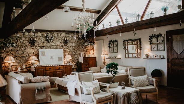 A cozy, rustic room with stone walls, wooden beams, and a chandelier. Furnishings include a sofa, armchairs, and a dining table. - Charming house - Montels - Occitanie Mediterranean (Montels)