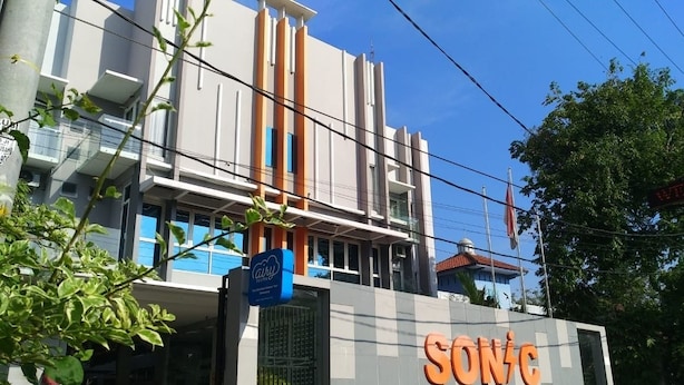 A modern building with a prominent 'SONIC' sign, a blue 'City' sign, and a visible balcony. - Hotel Sonic Airport Semarang (Semarang)