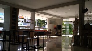 A spacious, modern interior with a bar area, seating, and a view of the outdoors. - Hotel Sonic Airport Semarang (Semarang)