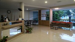 A spacious lobby with a reception desk, seating area, and a view of greenery outside. - Hotel Sonic Airport Semarang (Semarang)