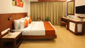 A hotel room with a bed, desk, chair, and a television. - Park Residency (Kanayannur)