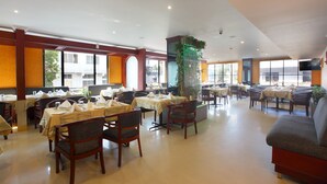 A spacious restaurant with multiple dining tables and chairs, large windows, and a modern interior design. - Park Residency (Kanayannur)