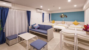 A modern hotel room with a sofa, two beds, a dining table, and a small balcony area. - Kariyushi Condominium Resort Miyakojima Fukugistays (Miyakojima)