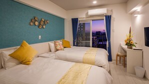 A hotel room with two beds, a desk with a chair, a window with curtains, an air conditioning unit, and a decorative wall piece. - Kariyushi Condominium Resort Miyakojima Fukugistays (Miyakojima)