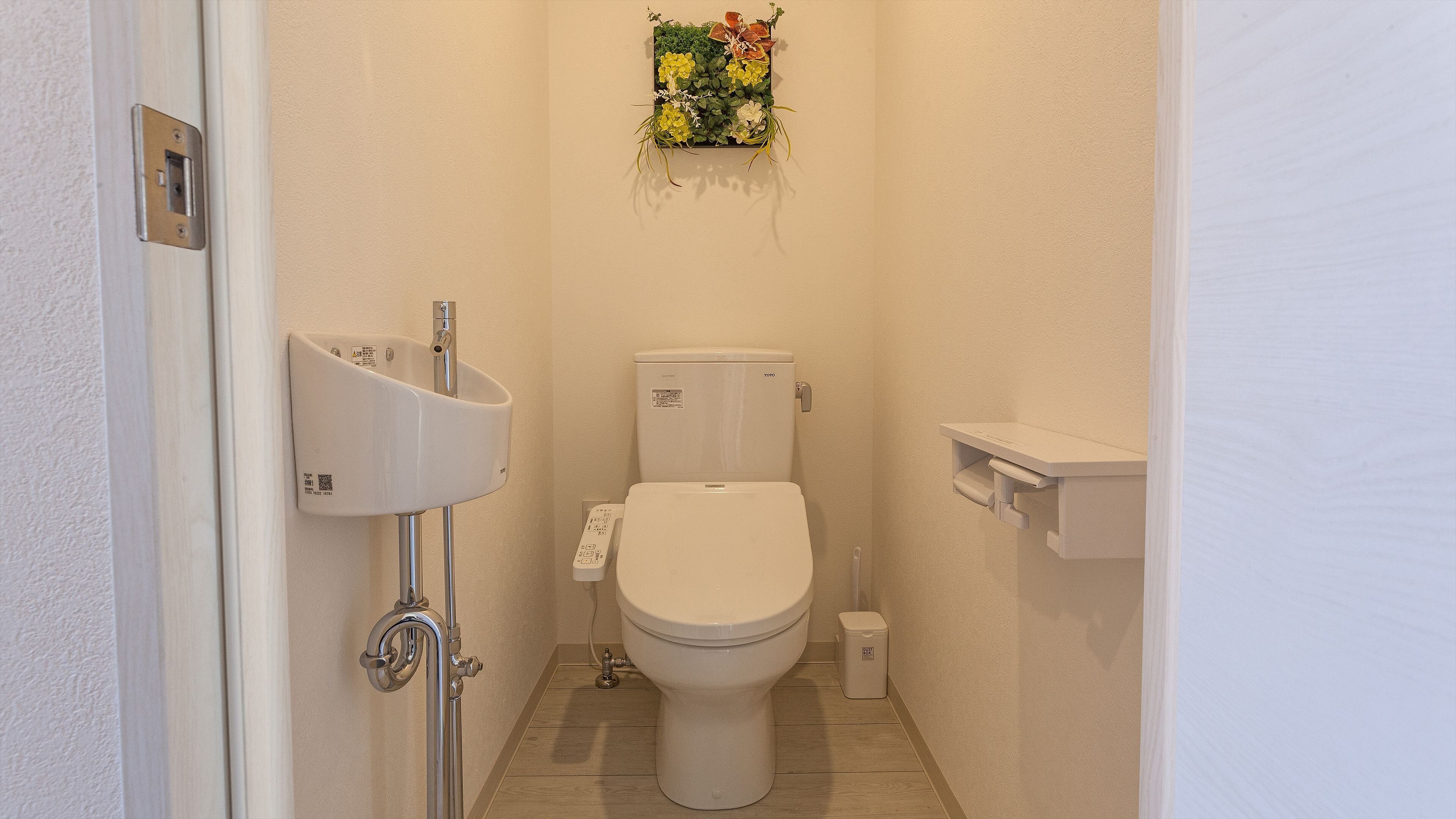 Un baño pequeño y limpio con inodoro, lavamanos y estante.