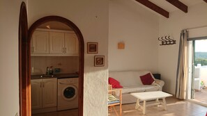 A compact living space with a kitchen, a sofa, and a small table.
