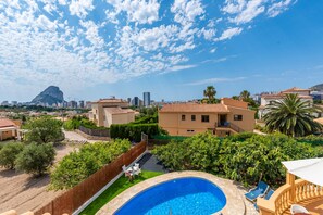 A residential area with a swimming pool, a view of a mountain, and a cityscape in the background. - Villa Serena - PlusHolidays (Calpe)