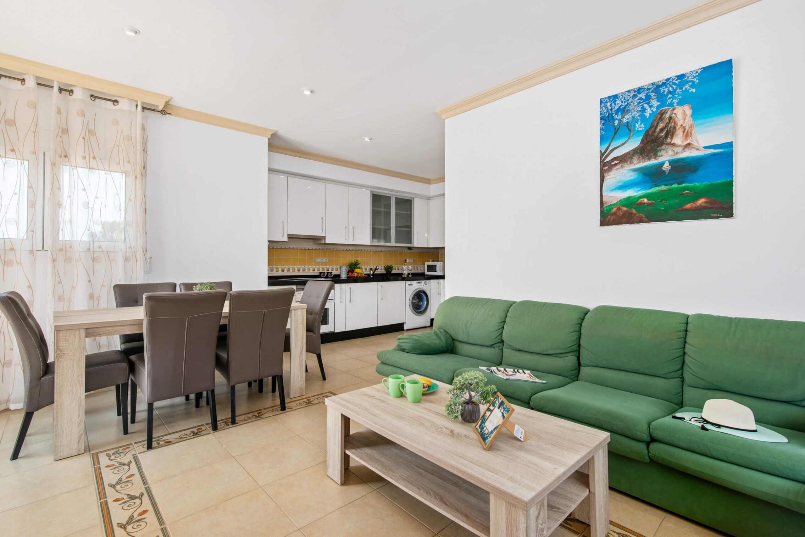 A modern living room with a green sofa, a wooden coffee table, and a dining area with chairs and a table.