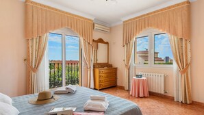 Quarto de hotel com cama, cômoda, espelho e janela com cortinas.
