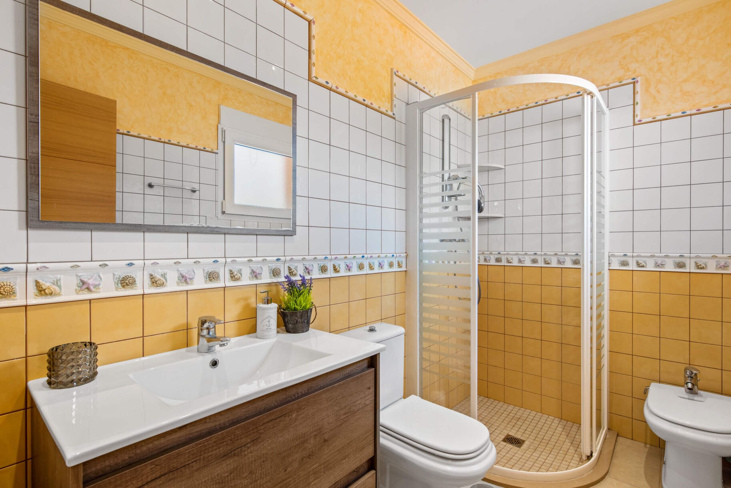 Ein Badezimmer mit weißem Waschbecken, Holzschrank, Toilette und Duschkabine.