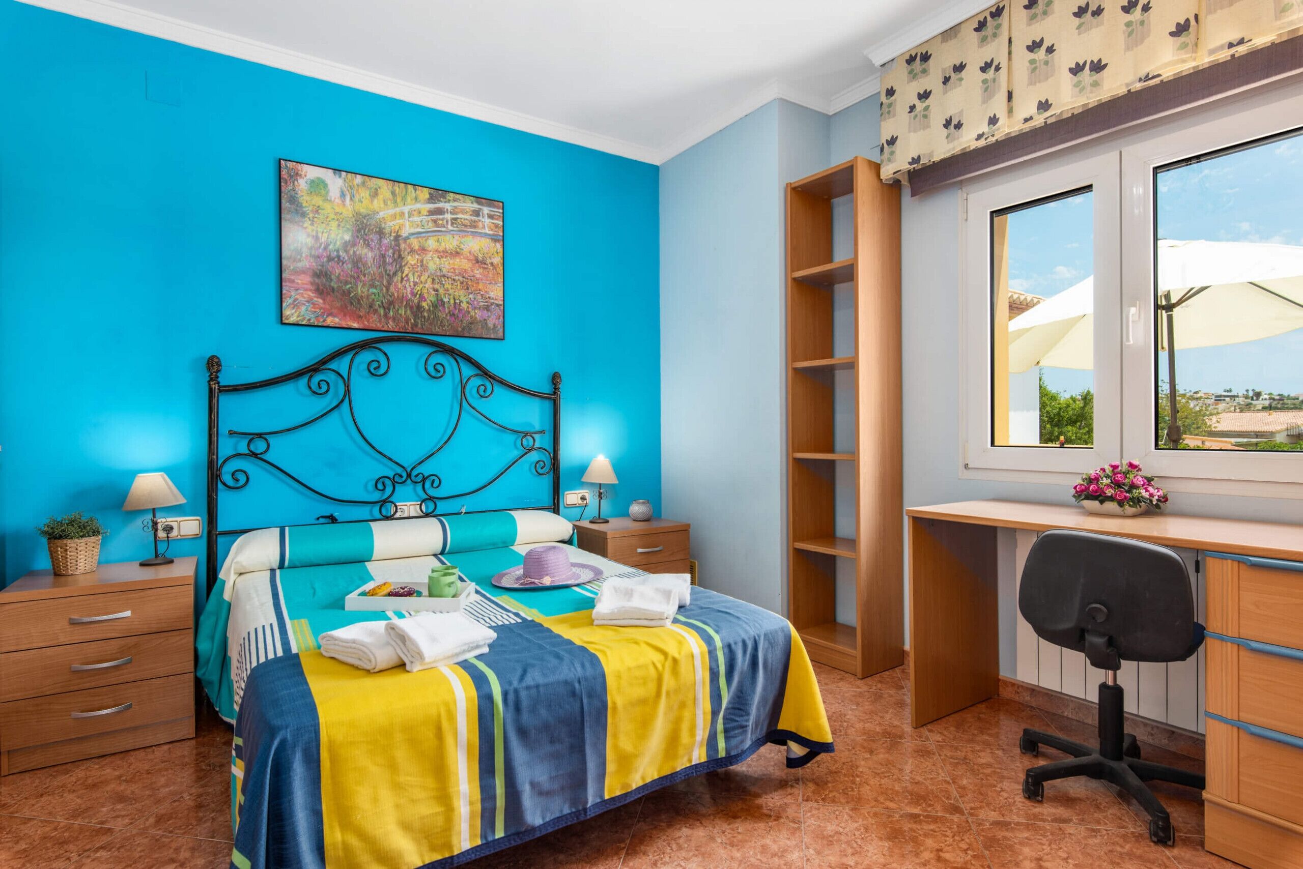 Une chambre à coucher comprenant un lit, des tables de chevet, un bureau et une chaise.