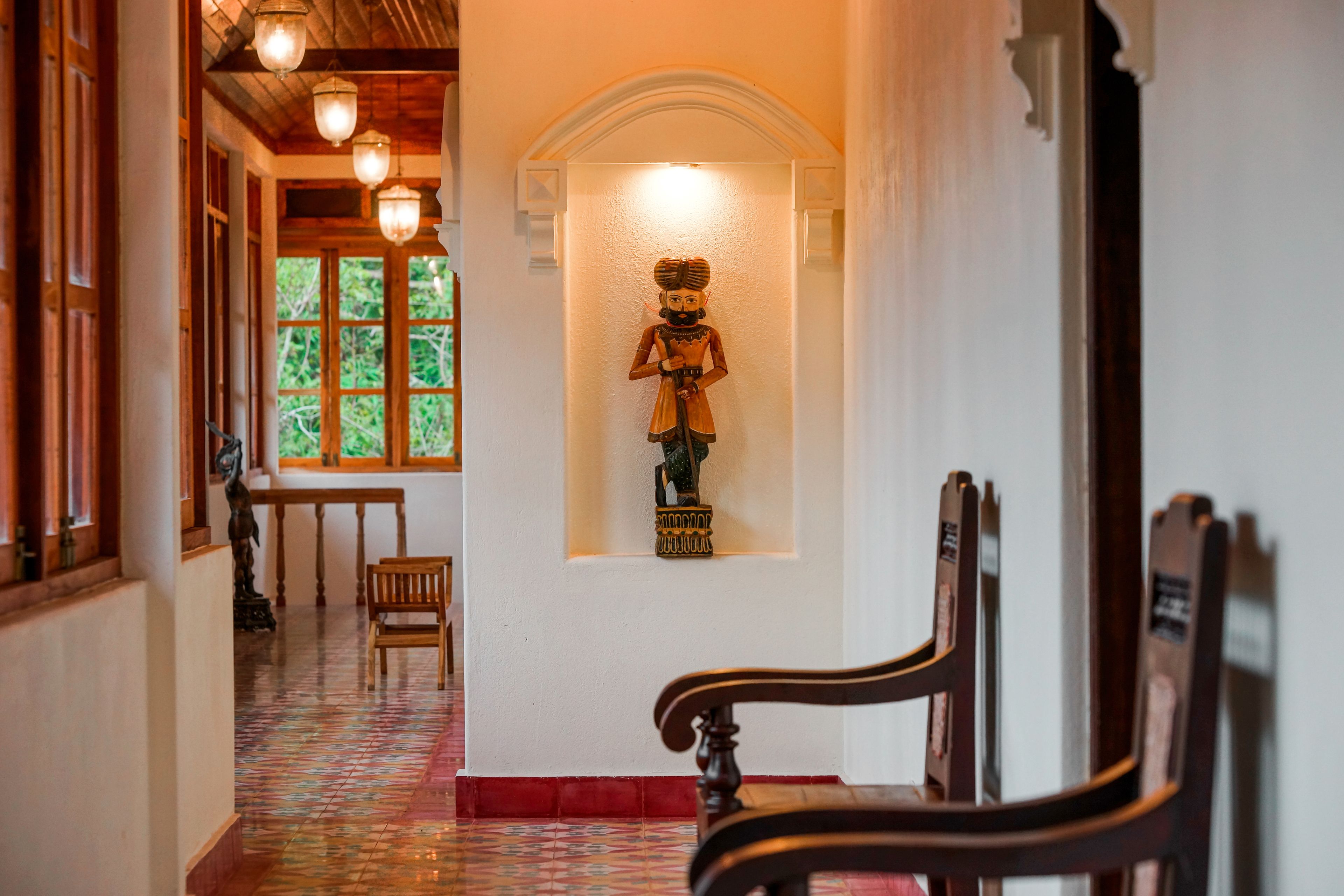 Un pasillo con una estatua, bancos de madera y baldosas de suelo con diseños.