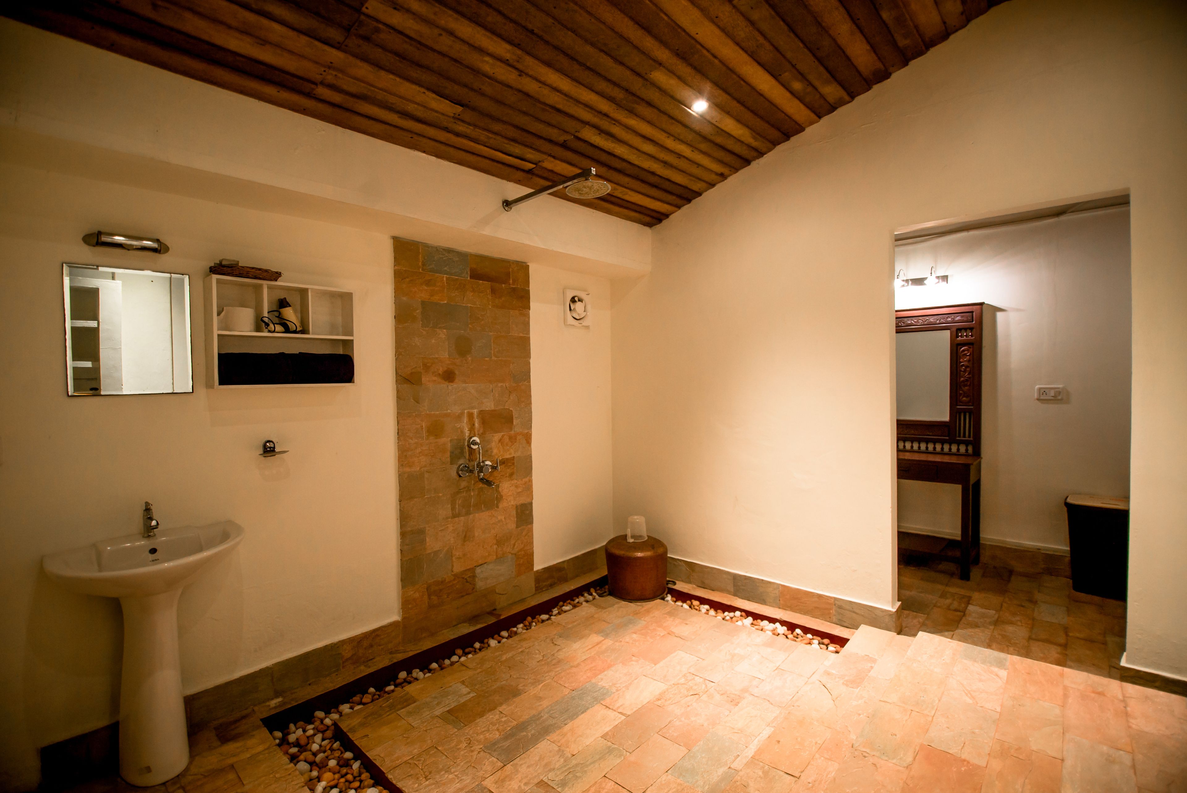 A bathroom with a stone shower, a sink, and a mirror.