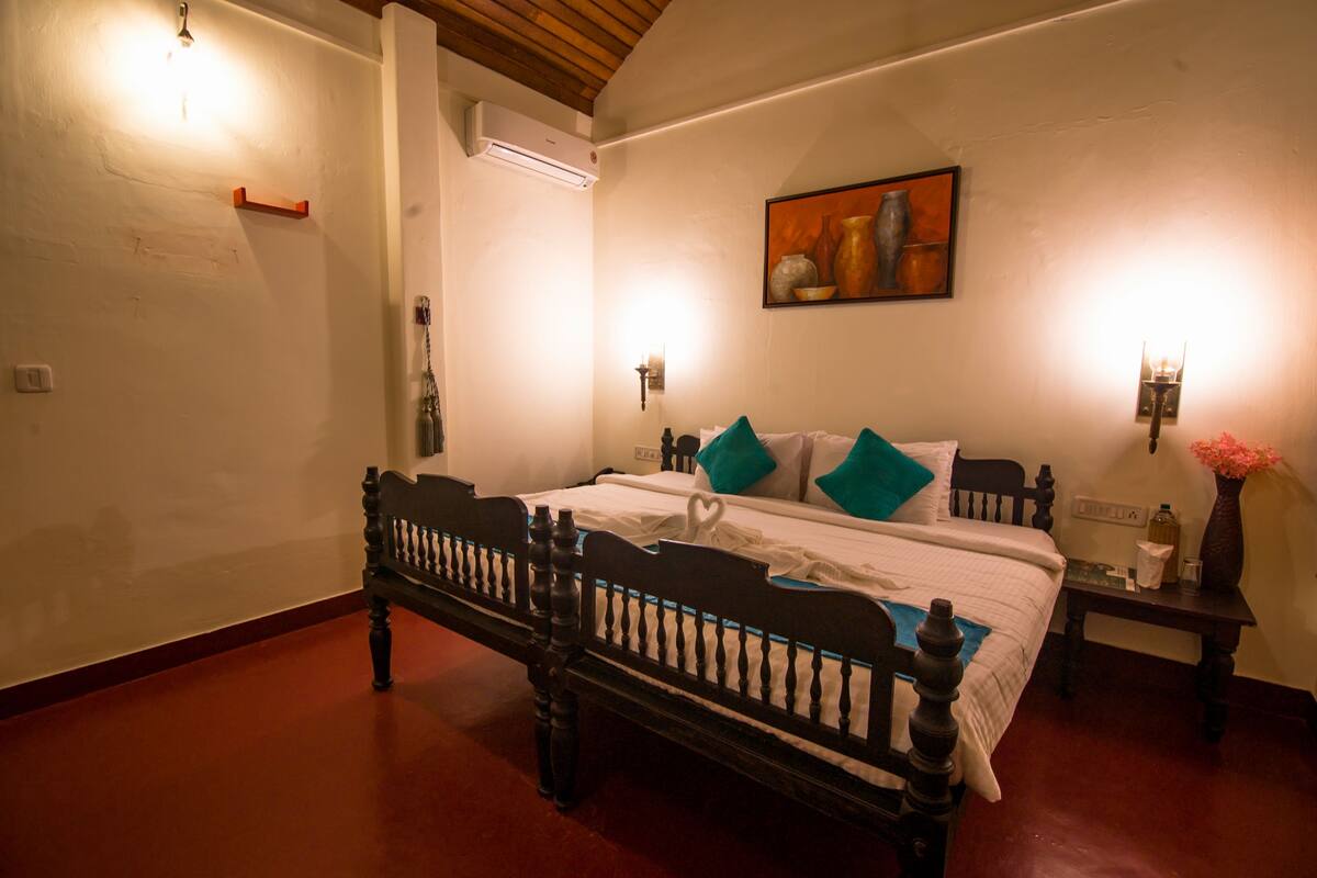 Een slaapkamer met een houten bed, witte wanden, een schilderij en twee wandlampen.