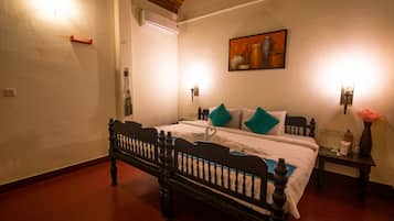 A bedroom with a wooden bed, white walls, a painting, and two wall-mounted lights.