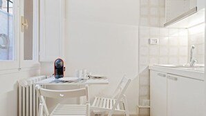 Eine kleine Küche mit weißen Schränken, einer weißen Arbeitsplatte, einem Spülbecken und einem Fenster mit Blick.