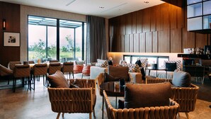A modern hotel lobby with a seating area, large windows, and a view of greenery. - Tsang Kuo Resort (Wujie)