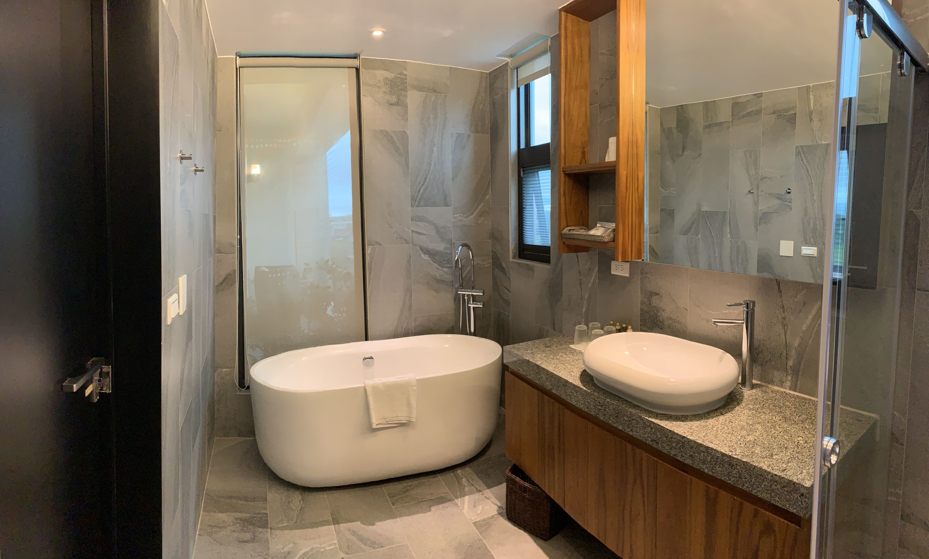Een moderne badkamer met een vrijstaand bad, een wastafelmeubel en een douchecabine van glas.