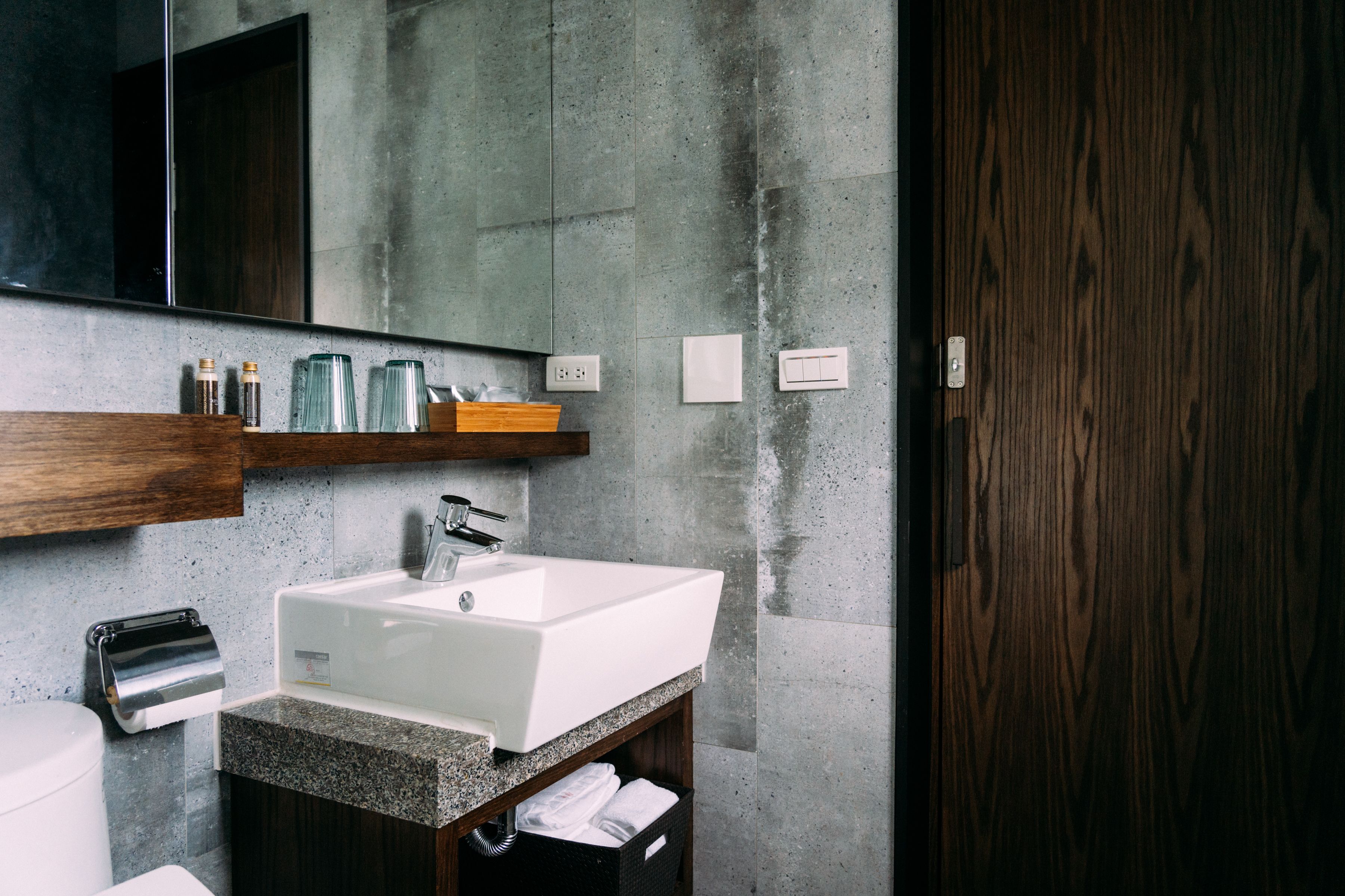 Un baño moderno con un espejo grande, un lavabo blanco y un mueble de tocador de madera.