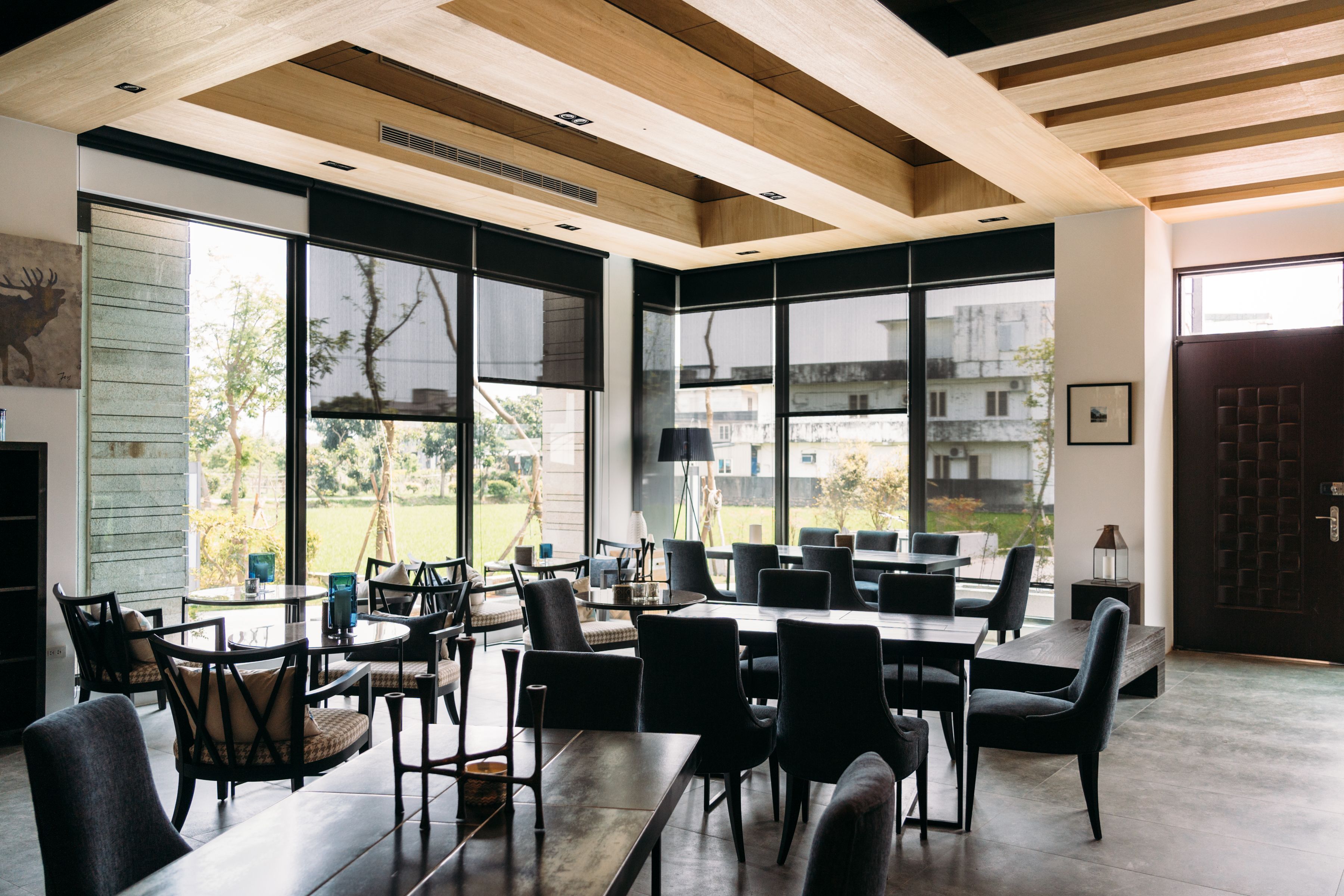 A spacious dining area with large windows, modern furniture, and a view of the outdoors.
