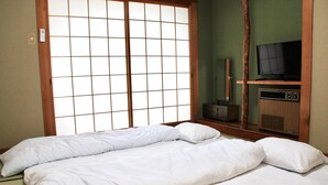 Une pièce dotée d’un paravent japonais traditionnel en papier, d’une télévision et d’une radio posées sur un meuble en bois.