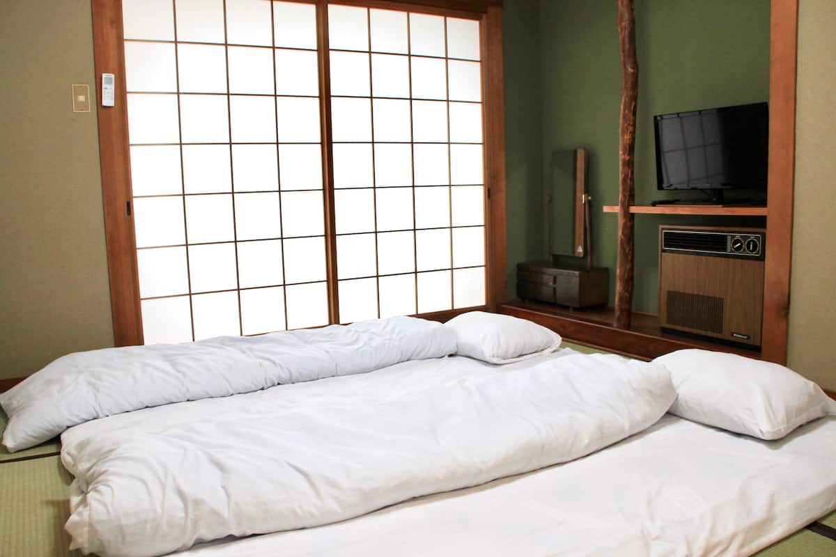 A room with a traditional Japanese shoji screen, a television, and a radio on a wooden cabinet.