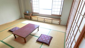 Une pièce avec un sol recouvert de tatamis, une petite table basse et deux coussins.