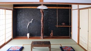 Une pièce de style japonais traditionnel, avec un sol recouvert de tatamis, une basse table en bois et un luminaire suspendu.
