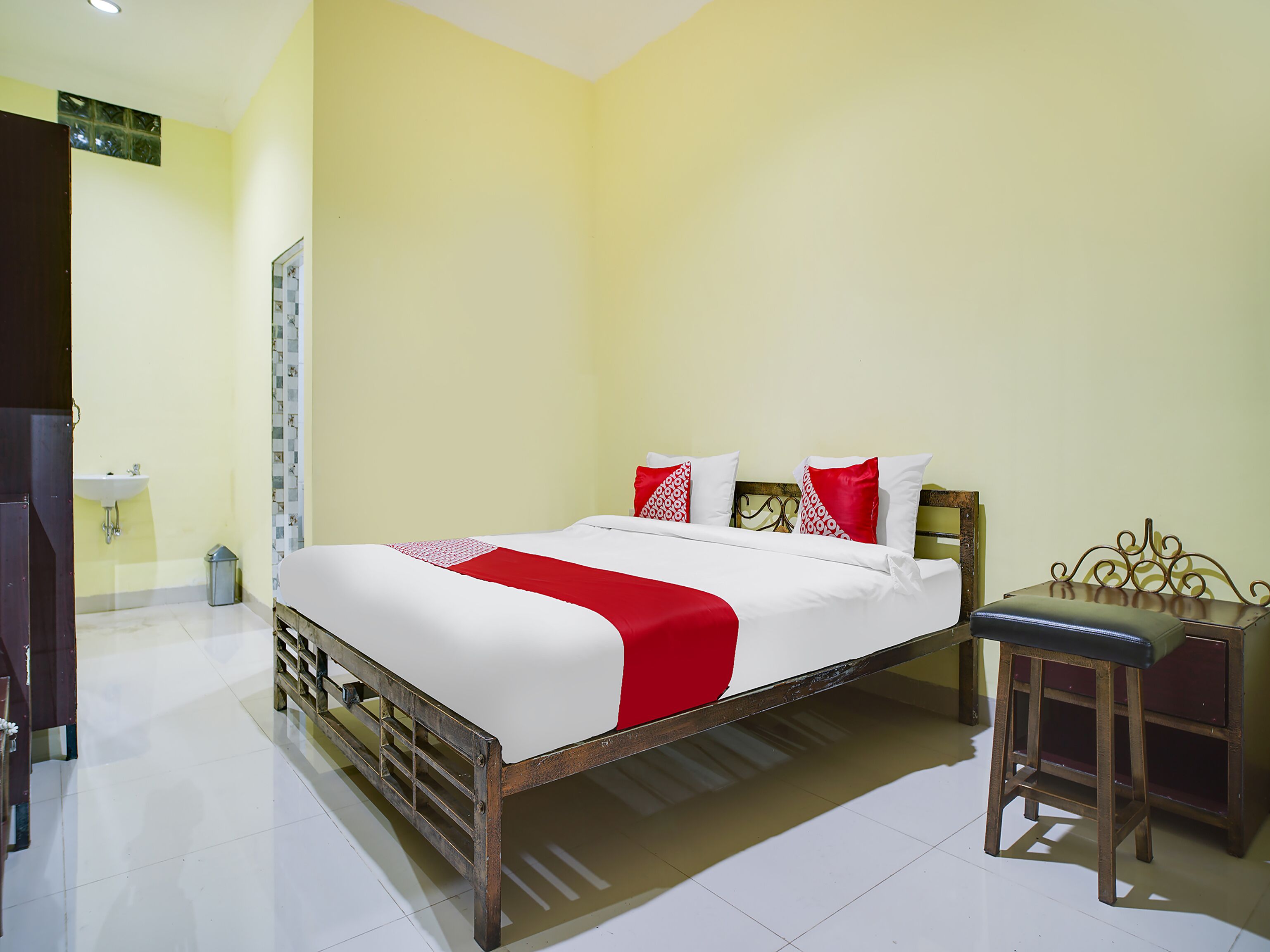 A hotel room with a bed, a nightstand, a desk, and a window.