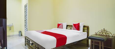 A hotel room with a bed, a nightstand, a desk, and a window.