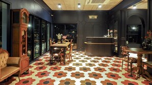 A room with a hexagonal patterned floor, a wooden reception desk, and a large window. - WIW Minihotel (Bangkok)